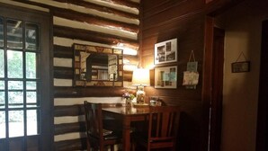Un interior rústico de madera con una mesa de comedor y sillas, un espejo y cuadros en la pared.