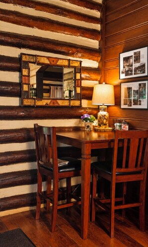 A wooden dining table with chairs, a mirror, and a lamp.