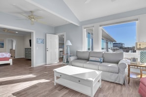 A spacious living room with a grey sofa, white coffee table, and a ceiling fan.