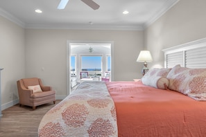 A bedroom with a large bed, a chair, and a view through an open door.
