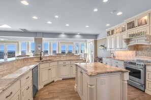 A spacious kitchen with a large island, built-in appliances, and a view of the city.