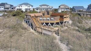Una propiedad frente al mar con una terraza de madera y varios niveles, rodeada de otras casas.