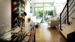Una sala de estar moderna con una mesa de comedor de cristal, sofás blancos y una escalera.