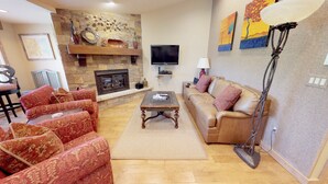 A living room with a fireplace, a sofa, a coffee table, and a television. - Terracehouse - Steps to Slopes | Inviting Mountain Retreat, Pool & Hot Tub (Snowmass Village)