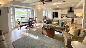 A spacious living room with a dining area, a kitchen, and a large sliding glass door leading to a deck. - Granbury Lake Rustic Retreat on Quiet Cove (Granbury)