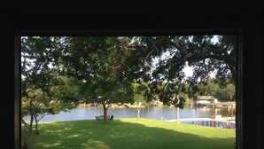 A view of a lake with a grassy area, benches, and a dock. - Granbury Lake Rustic Retreat on Quiet Cove (Granbury)