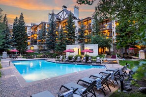 A resort with a swimming pool, lounge chairs, and a building with multiple balconies.