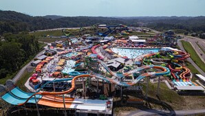 Een waterpark met meerdere glijbanen en zwembaden, omgeven door een heuvellandschap.