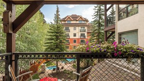 Un balcon offrant une vue sur un immeuble, une piscine et la végétation environnante.