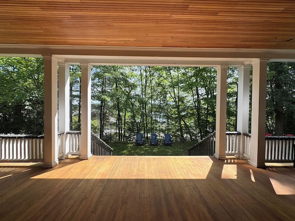 A covered wooden deck with a view of a forested area.