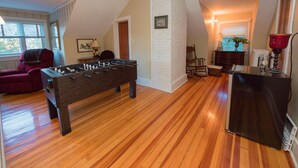 A room with a foosball table, a rocking chair, and a desk with a lamp.