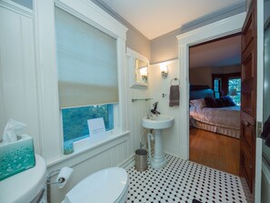 A bathroom with a toilet, sink, and window with blinds.