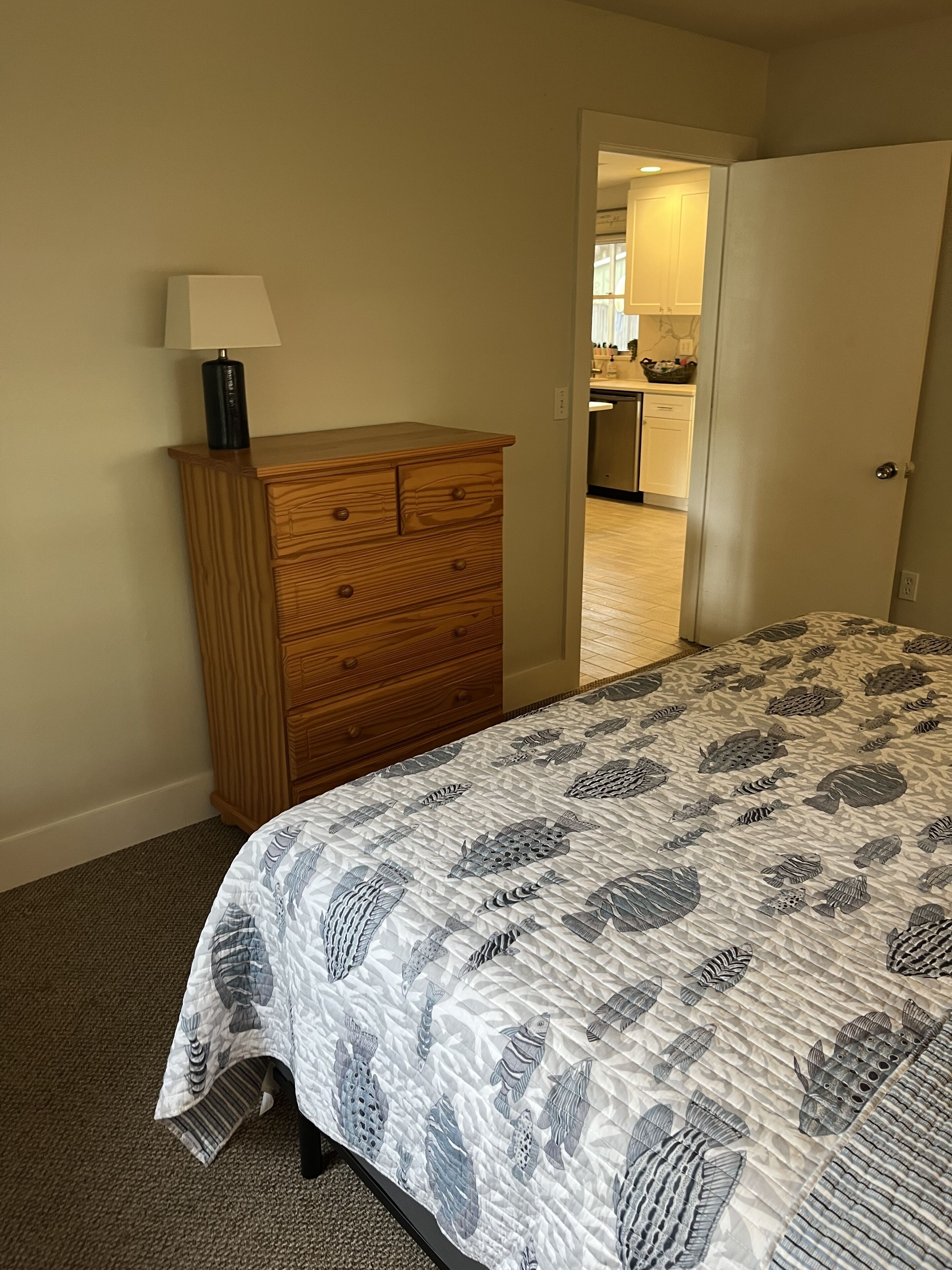 Une chambre à coucher avec un lit, une commode en bois et une lampe.