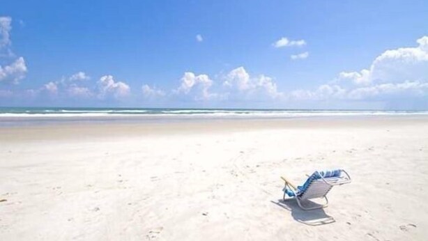 A beach with a single beach chair and a small table, under a clear sky. -  4 Bed pool House by Bay!  Lido & Siesta Key Beaches very close  (Sarasota)