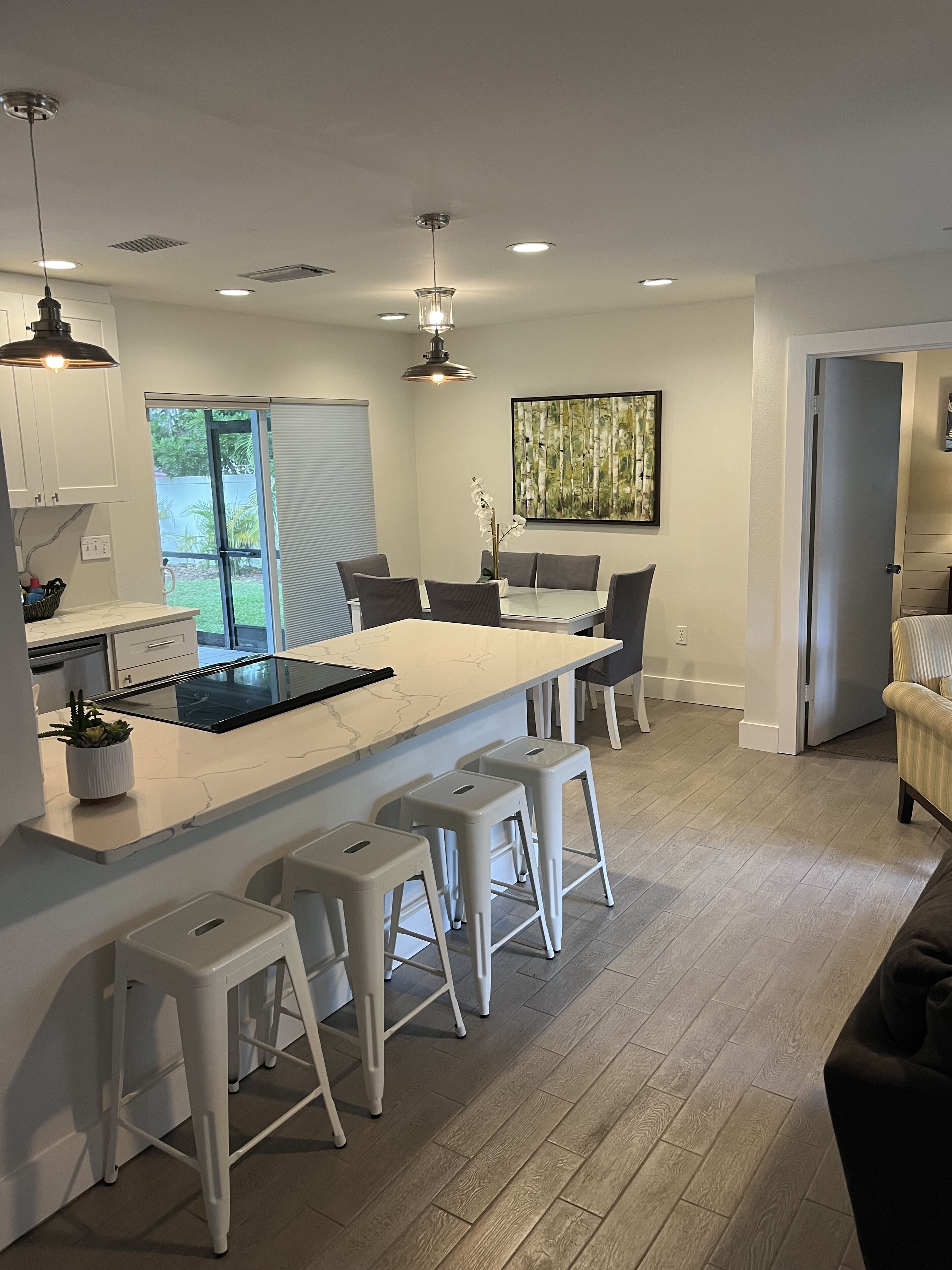 Una cocina moderna con una isla central, taburetes de bar y un comedor.