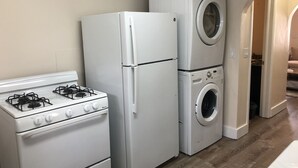 Een keuken met een fornuis, koelkast en wasmachine.
