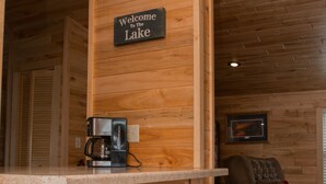 Ein Holzeinrichtung mit Barbereich, einer Kaffeemaschine und einem Schild mit dem Aufdruck 'Willkommen am See'.