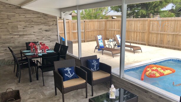 Un'area patio coperta con piscina, mobili da esterno e tavolo da pranzo.