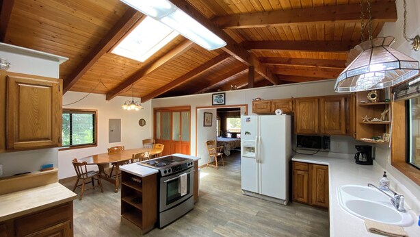 A spacious kitchen with wooden cabinets, a central island with a stove, a refrigerator, and a sink. - Beautiful Beach access/River Front Hot tub and Fire pit  (Brookings)