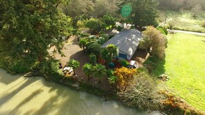 An aerial view of a house surrounded by dense greenery, with a small patio area and a swimming pool. - Beautiful Beach access/River Front Hot tub and Fire pit  (Brookings)