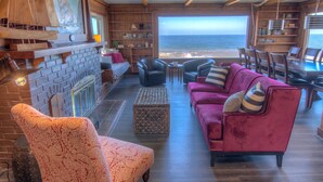 A cozy living room with a fireplace, comfortable seating, and a view of the ocean.