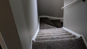 Een trap met een bekleed landingsvlak en een raam met uitzicht op groen.