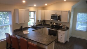 A modern kitchen with white cabinets, a stainless steel oven, and a granite countertop. - Falmouth Waterfront Carriage House Apt (Falmouth)
