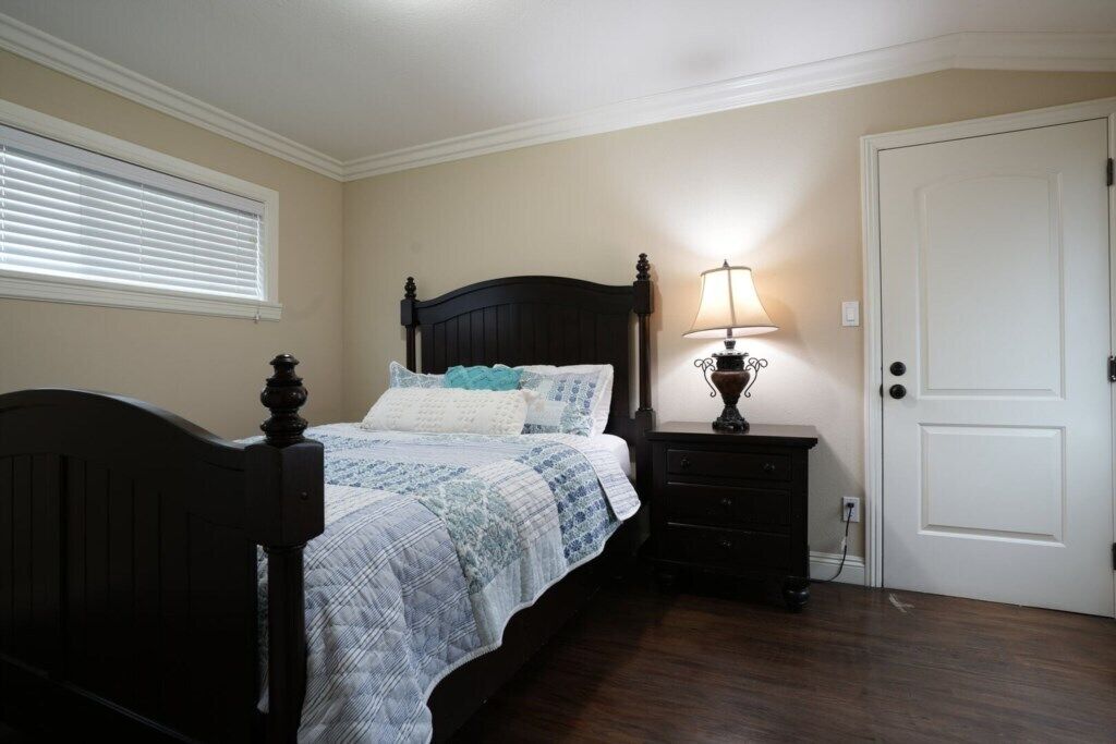 Une chambre à coucher avec un lit, une table de chevet, une lampe et une porte.