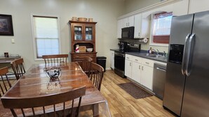 Una cocina con una mesa de comedor, sillas, un refrigerador, un microondas y un armario.