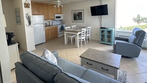 Una sala de estar moderna con un sofá gris, una mesa de centro y una zona de comedor con una mesa y sillas.