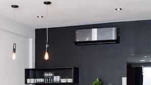 Une cuisine moderne dotée d’un îlot central, d’appareils électroménagers intégrés et de luminaires suspendus.