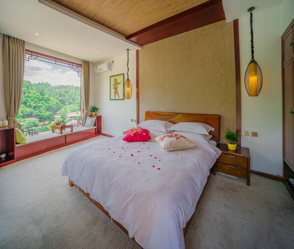 Un dormitorio amplio con una cama grande, vistas al verdor exterior y un techo de madera.