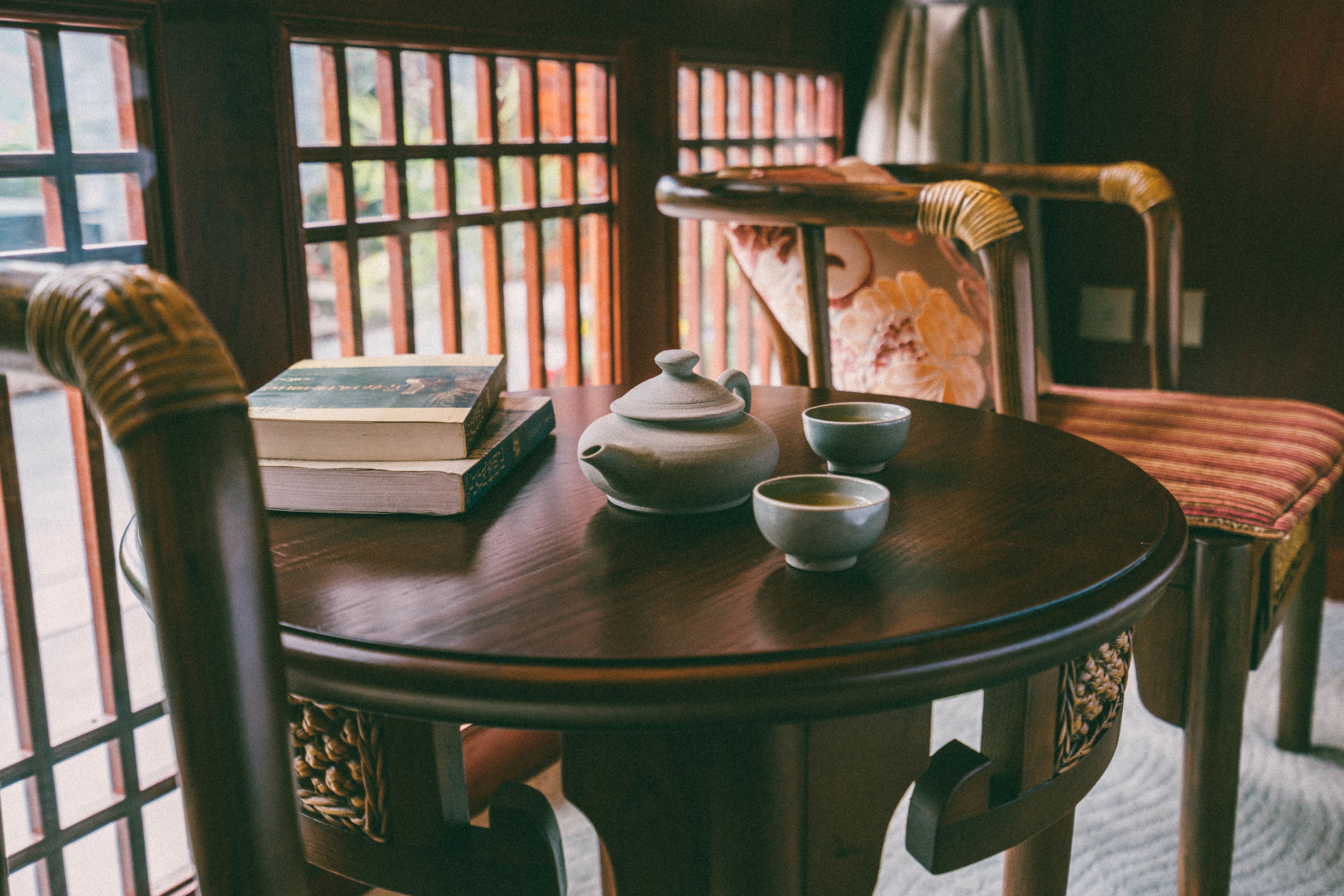 Une table en bois avec une théière, deux tasses et un livre.