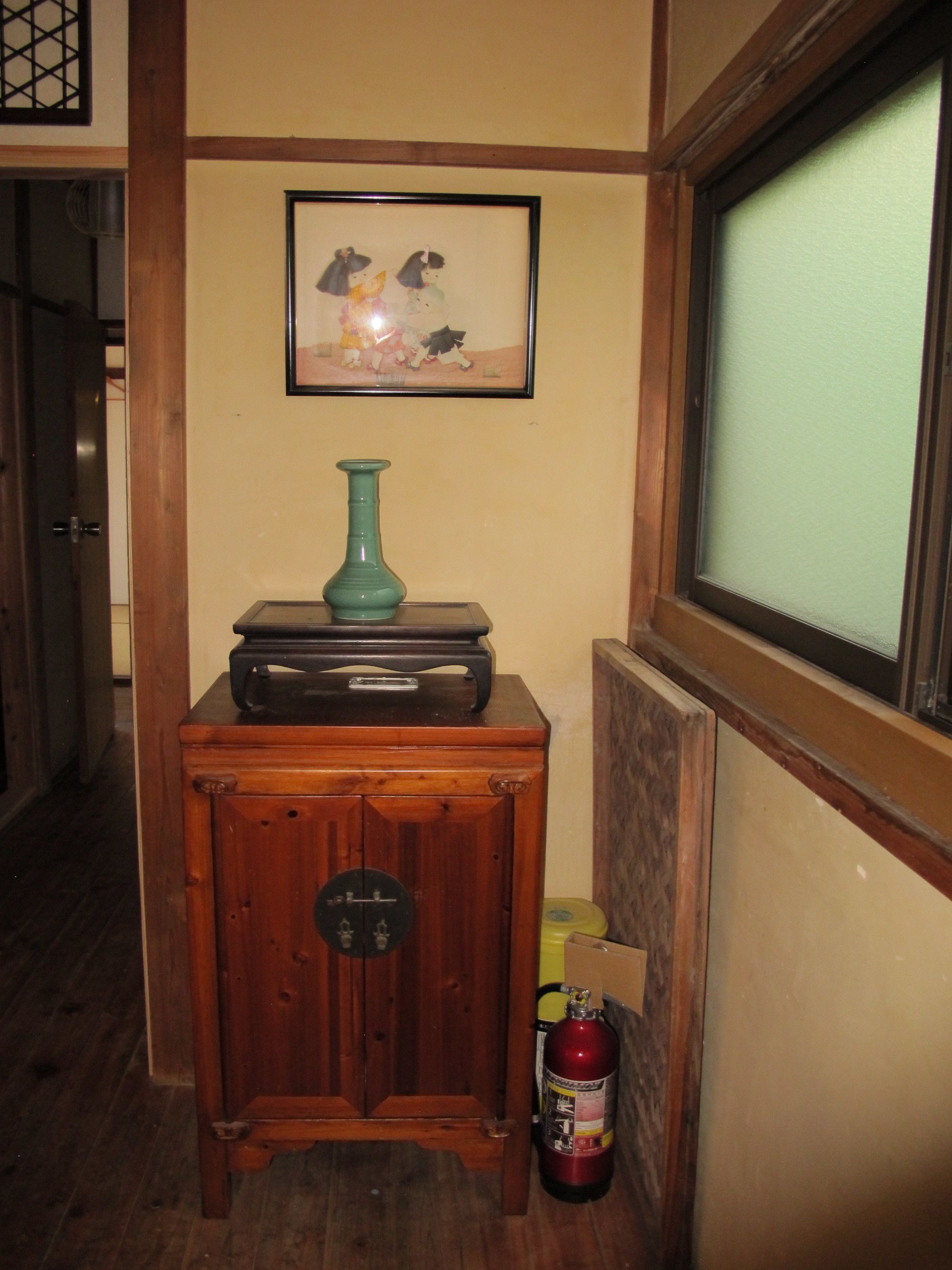 A wooden cabinet with a vintage radio, a framed picture, and a fire extinguisher.