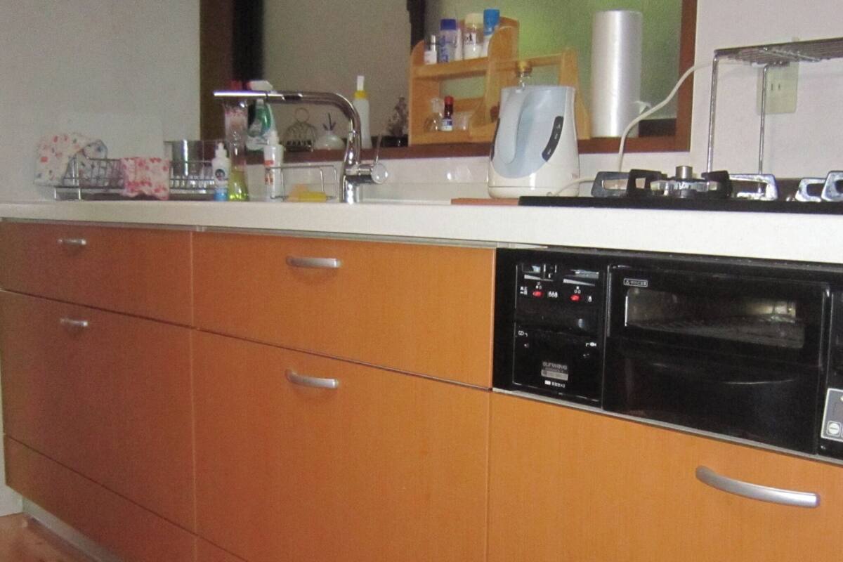 Una cocina con armarios de madera, lavavajillas, cafetera y microondas.