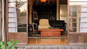 A room with a wooden bench, a black sofa, and a framed picture on the wall. - Atami Ikkyuan (Atami)