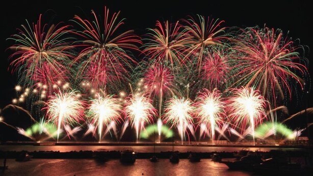A nighttime fireworks display over a body of water with reflections on the surface. - Atami Ikkyuan (Atami)