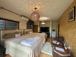 A bedroom with two beds, a television, a microwave, and a wooden chair. - Atami Ikkyuan (Atami)
