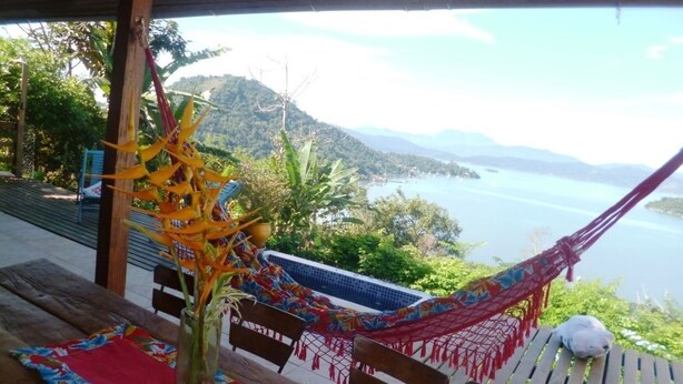 A hammock under a wooden structure with a view of a lake and mountains. - Charming House With Stunning Views (Paraty)