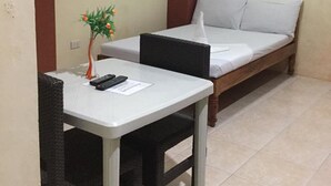 Ein kleines Zimmer mit einem Einzelbett und einem Tisch mit Stühlen.