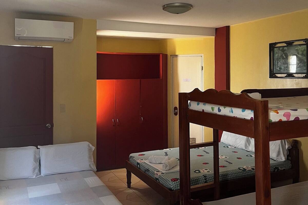 A hotel room with a bed, a wooden chair, a wardrobe, and a television.