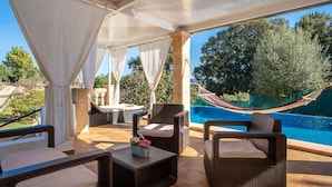 Un espace extérieur aménagé avec des meubles en osier, une piscine et un hamac.