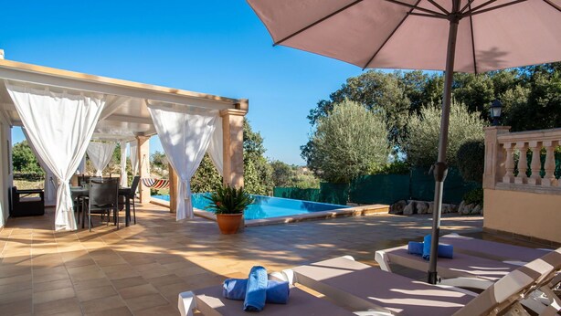 Un espace extérieur abrité comprenant une piscine, des chaises longues et une table avec des chaises.
