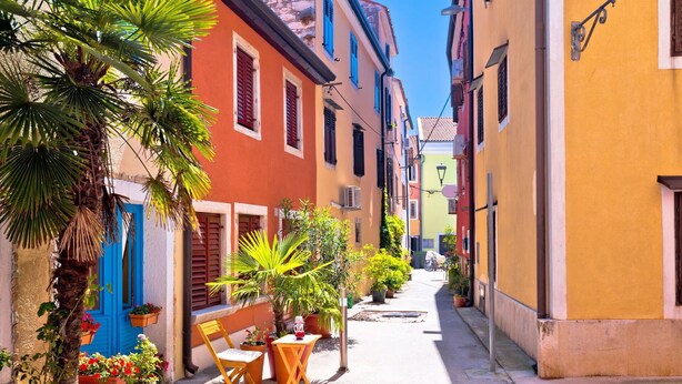 A narrow street with colorful buildings, outdoor seating, and potted plants. - Beautiful  villa for 8 people with A/C, private pool, WIFI, TV and terrace (Umag)