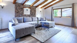 A modern living room with a sectional sofa, a small coffee table, and a stone accent wall. - Beautiful  villa for 8 people with A/C, private pool, WIFI, TV and terrace (Umag)