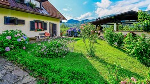 A traditional chalet with a sloped roof, a wooden deck, and a garden with various plants and flowers. - Beautiful private villa for 6 guests with WIFI, private pool, A/C, TV, terrace and panoramic view (Brod Na Kupi)