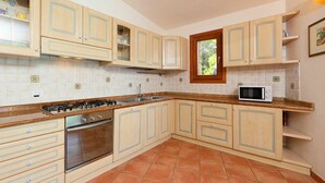 Eine Küche mit Holzausstattung, einem Gasherd, einem Backofen und einer Mikrowelle.