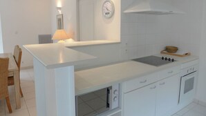 A modern kitchen with white cabinetry, a built-in oven, a gas stove, and a clock on the wall. - Wonderful private villa for 8 guests with private pool, WIFI, TV and terrace (Lacanau-océan)