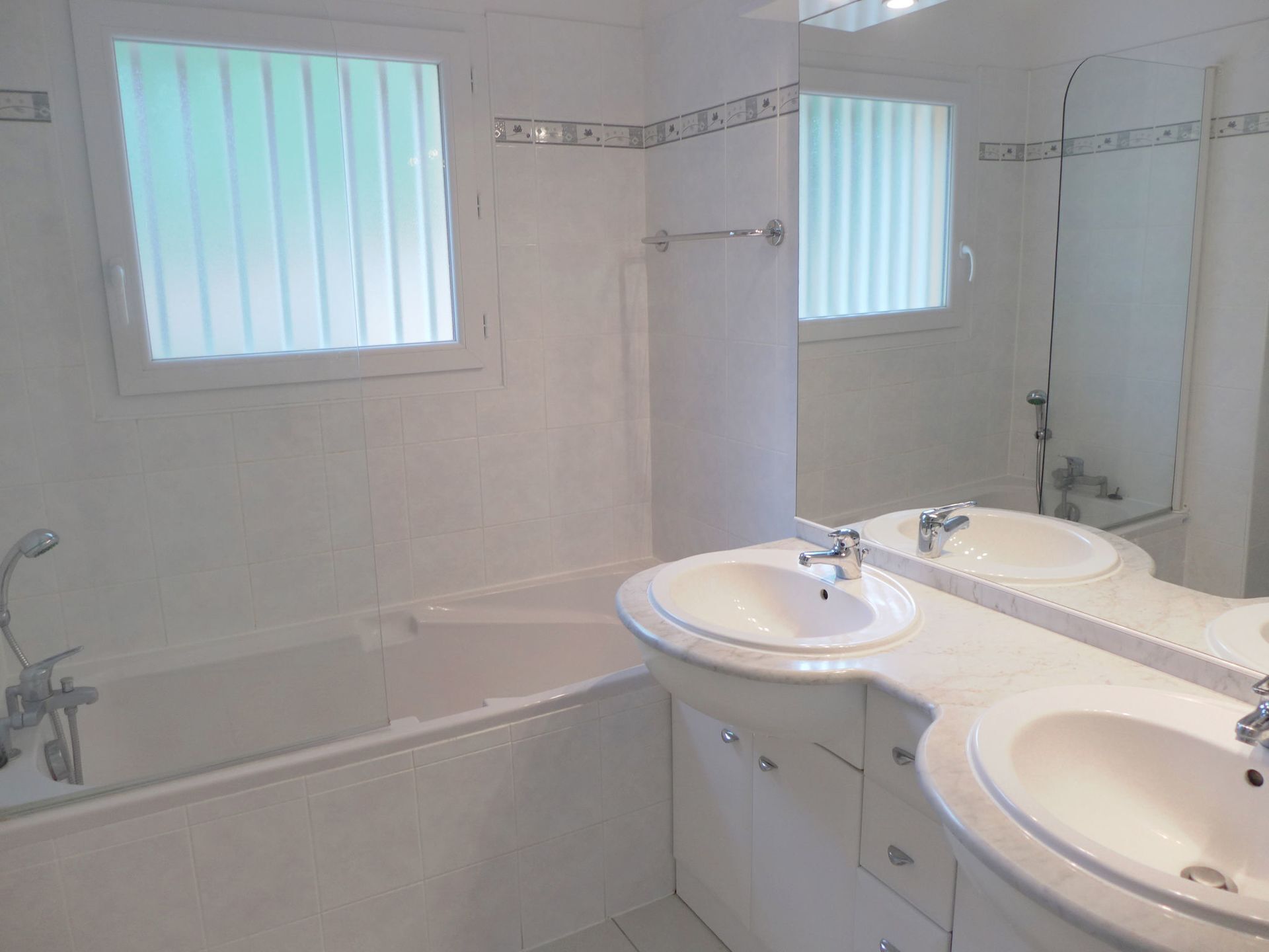 Ein Badezimmer mit einer Badewanne, zwei Waschbecken und einem großen Spiegel.