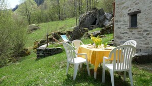Un bâtiment en pierre avec une petite table et quatre chaises blanches disposées à l’extérieur.